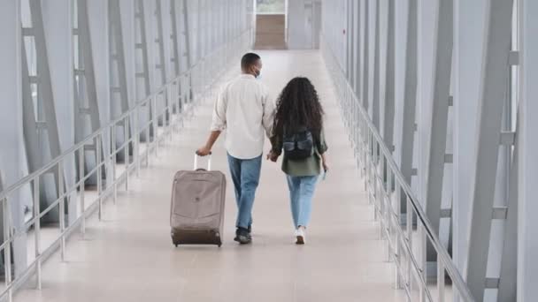 Deux jeunes amoureux voyageant ensemble. Heureux couple multiracial se rend à l'aéroport terminal avec des bagages. Homme africain et femme caucasienne tenant la main marchant en station avec valise et sac à dos — Video