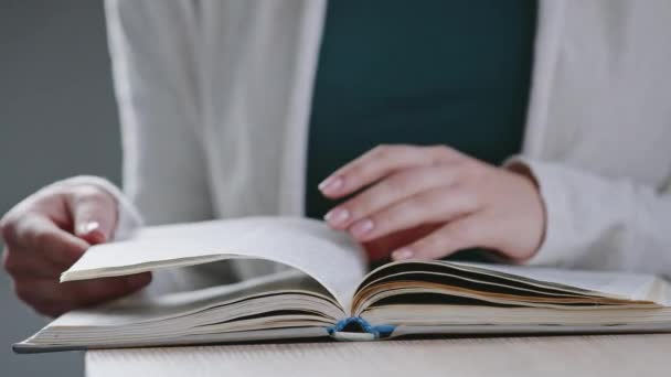 Primer plano manos femeninas de joven irreconocible mujer caucásica estudiante chica vueltas páginas en diccionario libro lectura literatura lee libro de texto estudiar sentado en la mesa en la universidad, vista recortada — Vídeo de stock