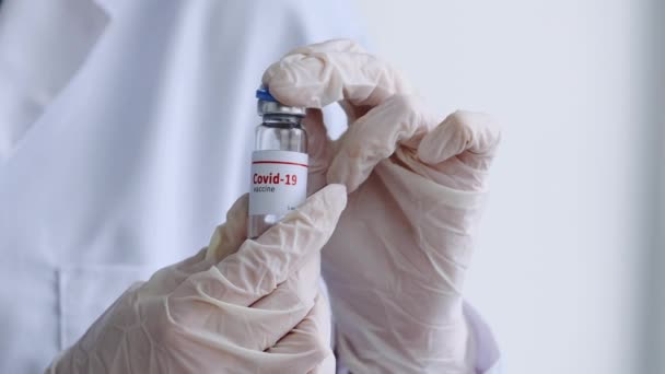 Κοντινό πλάνο γυναικεία χέρια νοσοκόμου ιατρού που κρατά ένα μπουκάλι covid 19 εμβόλιο ανοιχτό βάζο του φαρμάκου coronavirus υγρό αντιβιοτικό φάρμακο, έννοια της φαρμακολογίας και την καταπολέμηση της γρίππης covid-19 — Αρχείο Βίντεο