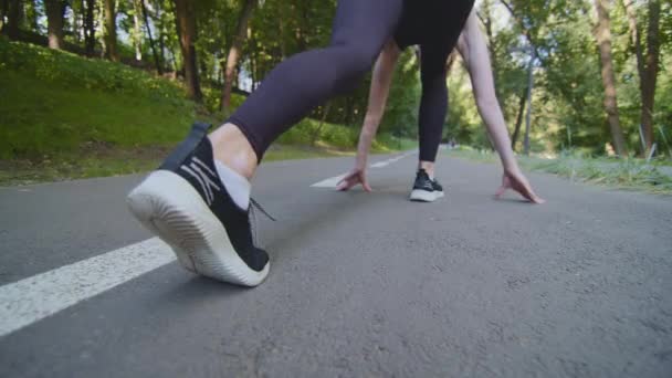 Gros plan des jambes féminines debout sur la piste au départ avant de courir la distance du marathon. Coup de feu récolté mince forte femme caucasienne active jogger cours de jogging dans le parc en plein air faire de l'entraînement sportif — Video