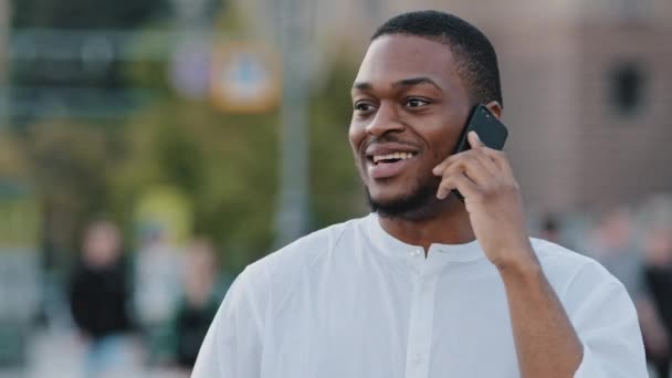 Африканский американец смешанной расы афро парень этнического мужчины студент внештатный предприниматель босс пользователь, говорящий по мобильному телефону смартфон отвечая на звонок стоя на улице в городе вызова беспроводного устройства — стоковое видео