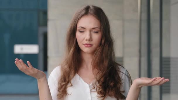Kobieta portret zbliżenie kaukaskie millenium kobieta dziewczyna zastanowiony mylić pani stoi na zewnątrz na ulicy robi ciężary gestem z rąk myśli sprawia, że decyzja porównuje dwie opcje wzrusza ramionami — Wideo stockowe