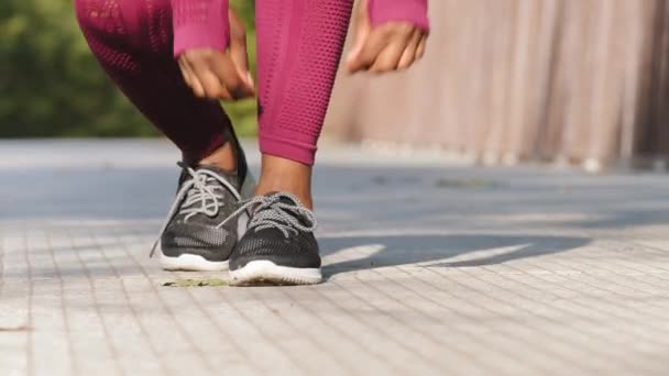 Africana hembra negra termina carrera se detiene se inclina para atar cordones de zapatos en zapatillas de running. Mujer atleta preparándose para correr al aire libre. Corredor preparándose para el entrenamiento. Deporte concepto de estilo de vida activo — Vídeo de stock