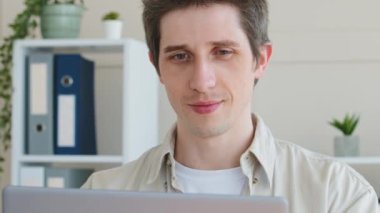 Genç Kafkas erkek serbest çalışan milenyum yetişkin iş adamı müşteri kullanıcısı laptop ekranına bakıyor internetten alışveriş yapıyor internet sohbet ağı kuruyor ev ofisinin masasında oturuyor.