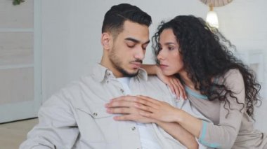 Portre İspanyol 'u gücendirdi. Üzgün, stresli İspanyol adam. Kafkasyalı eşe kırgınlık duyuyor. Kanepede oturan çok ırklı çift.
