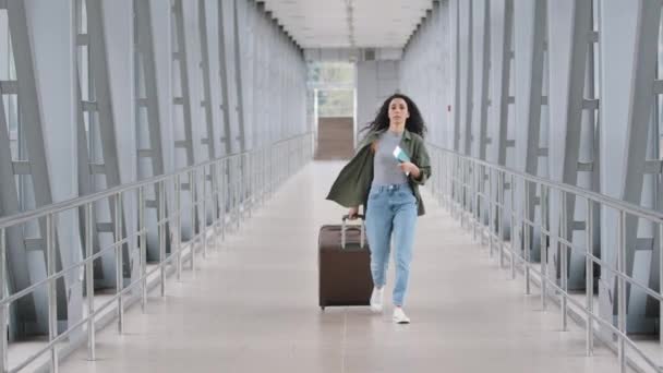 Jonge Kaukasische dame meisje vrouw vrouwelijke passagier toerist reiziger met koffer duwen vervoert bagage lopen rush op de luchthaven terminal station te laat voor vlucht instappen vliegtuig bezorgd — Stockvideo