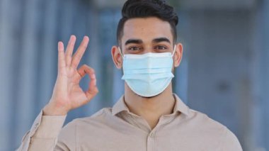 Portre ispanyol mutlu adam sorumlu hasta hasta adam erkek yüzüne tıbbi koruyucu maske takıyor dışarı poz veriyor tamam jest yapıyor her şey mükemmel el işareti