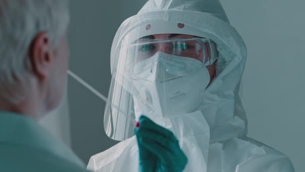 Portrait of blue-eyed woman doctor scientist medical nurse holding cotton swab in hand takes sample of infectious saliva PCR test analysis for covid19 diagnoses coronavirus in unrecognizable old lady — Stock Video