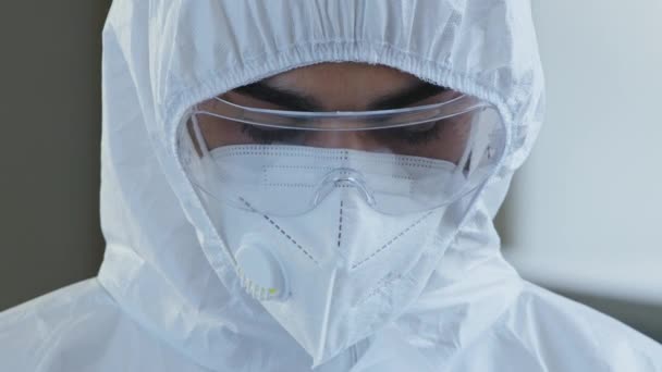 Ritratto di medico infermiere scienziato medico lavoratore indossa speciali occhiali protettivi bianchi tuta chimica uniforme e respiratore guardando la fotocamera con espressione triste, combattendo la pandemia covid-19 — Video Stock