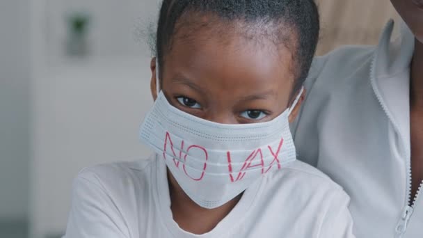 Portrait triste effrayé fille grave enfant bouleversé afro-américaine fille africaine noir ethnique bébé porte un masque de protection médicale avec inscription aucune protestation vaccinale contre la vaccination contre le coronavirus covid-19 — Video