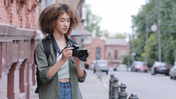 Positiv ung afrikansk amerikansk pige turist besøger maleriske by gade destination, ved hjælp af kamera tager billeder på sommerferie, udendørs. Sort biracial kvinde rejser teknologi rekreation – Stock-video