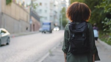 Afro saçlı ve sırt çantalı genç Afrikalı Amerikalı turist yolda tek başına yürüyor, hafta sonunun keyfini çıkarıyor, yabancı bir ülkede seyahat ediyor. Tek başına seyahat, seyahat kavramı