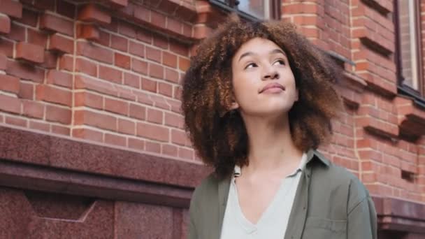 Jovem atraente menina negra mestiça andando no centro da cidade, sonhando acordado, turista olhando para edifícios, admirando a arquitetura, desfrutando de tempo livre em viagem de fim de semana no exterior. Conceito de viagem individual independente — Vídeo de Stock