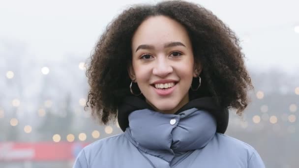 Front closeup portrait of authentic mixed race girl African American black woman with curly hair afro style standing on street at cold weather, looking at camera. Human face ideal natural make up skin — Stock Video