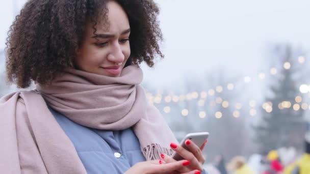 Portrait of happy business woman enjoy success on mobile phone standing outdoors. Closeup joyful afro american girl reading good news on smartphone at wintertime shows thumb up positive gesture — Stock Video
