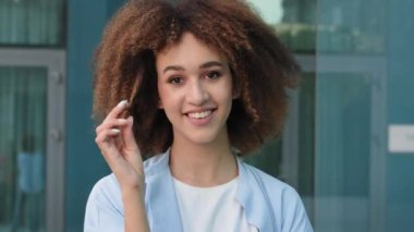 Kadın portresi. Güzel, baştan çıkarıcı, genç, etnik, afro-amerikan bayan model, afrikalı kadın. Sokakta durup kamera kıvrımlı saçlara bakıyor.