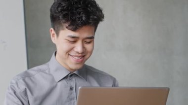 İçerideki Asyalı erkek portresi Koreli genç iş adamı Çinli Japon yönetici ofis çalışanı patron iş adamı iş için dizüstü bilgisayar ekranı ekranlarına bakıyor internette komik haberler okuyor