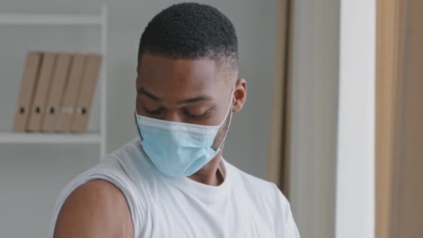 Przenoszenie materiału afrykański chory człowiek pacjent nosi maskę ochronną twarzy punkty palec na plastrze medycznym na ramię szczepienie znak zastrzyk umieszcza kciuki do góry zatwierdza szczepienie zadowolony z leków — Wideo stockowe
