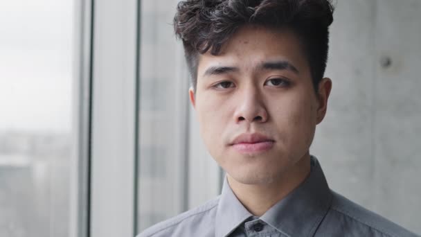 Male portrait serious sad upset asian business man chinese japanese guy student boss leader manager office worker wears formal shirt standing near window looking at camera with frustrated expression — Stock Video