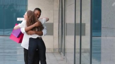 Beyaz, genç, alışverişçi kadın, Afro-Amerikan bir adamla buluşmaya gidiyor. Alışveriş paketlerini gösteriyor. Sarılıyor, afro çocuğa sarılıyor, hediyeler veriyor.
