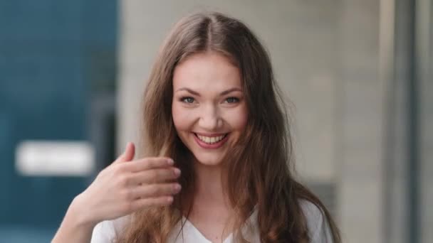 Retrato feminino ao ar livre bonito amigável sorrindo sedutor flertando menina milenar senhora de pé na cidade fazendo um gesto de convite com a mão chamando venha convidando chamada de sinal de boas-vindas aqui — Vídeo de Stock