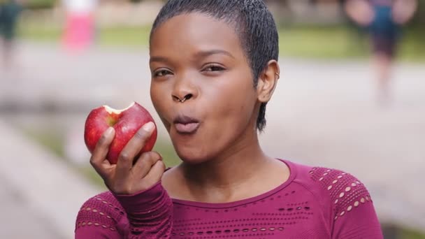 Bella giovane atletica ragazza millenaria nera con piacere di mangiare deliziosa mela, scegliere cibo sano, controllare il peso. Felice razza mista femminile imposta esempio ai giovani promuove stili di vita sani — Video Stock