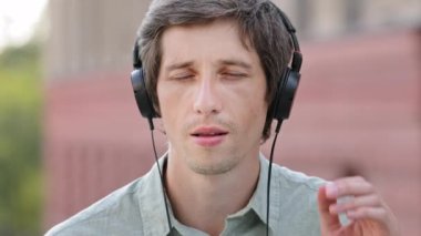 Kulaklıklı mutlu bir milenyum adamı müzikten hoşlanır, modern kulaklıklı gülümseyen beyaz bir erkek favori şarkıları dinler, kapalı gözlerle kaliteli sesten zevk alır. Yapımcı yeni şarkı dinliyor