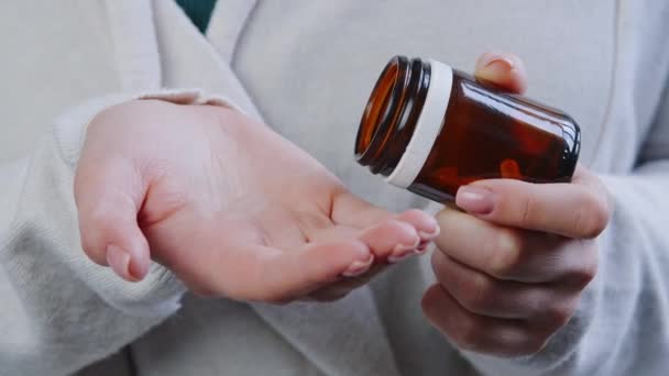 Κοντινό πλάνο αγνώριστο άρρωστος καυκάσιος ασθενής γυναίκα φοράει μάλλινο πουλόβερ κατέχει βάζο με χάπια λαμβάνοντας θεραπεία φάρμακο στο χέρι ρίχνει τρεις κάψουλες από μπουκάλι φάρμακα, φαρμακείο και θεραπεία έννοια — Αρχείο Βίντεο
