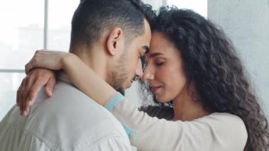 Çok ırklı İspanyol bir çift, yeni evli, beyaz tenli, esmer bir eş ve sarılıp kucaklaşan, kucaklayan, kucaklayan, alnına dokunan, sevgi dolu bir koca.