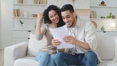 Öforik İspanyol çift koltukta oturup harika haber bankasının onaylı kağıt mektubu okuyor. Kârlı bir iş fırsatı sunuyor. Kutlama başarısı, sarılma, zafer jesti.
