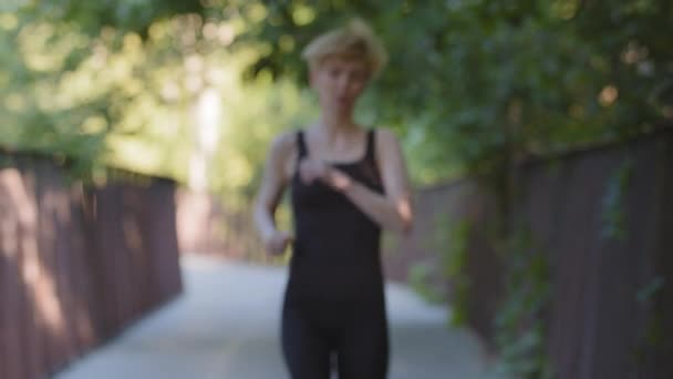 Atletische sterke actieve vrouw slanke dame loper vrouwelijke jogger trainer sportvrouw rennen in het park op de brug buiten doen 's morgens joggen cardiotraining sport workout voelt moe uitputting stopt — Stockvideo