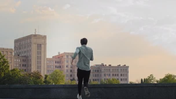 Joven hombre feliz corriendo, saltando, levantando las manos, sintiéndose libre, satisfecho con el trabajo hecho, yendo a la universidad, recibiendo beca o subvención. Millennial chico celebrando el éxito, victoria, fecha de la suerte — Vídeo de stock