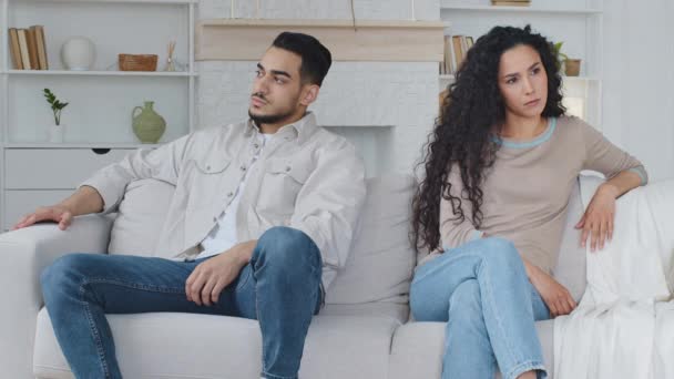 悲しい白人の妻、ボーイフレンドとガールフレンドとは別にソファに座っている怒っているアラビア人の男は、ソファの上に座って自宅で誤解を争う。結婚した夫婦はお互いを無視して — ストック動画