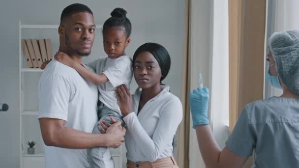 Grave famiglia afro-americana genitori neri in possesso di figlia afro ragazza in piedi in laboratorio ospedaliero con espressioni di paura preoccupato per la vaccinazione iniezione vicino medico infermiere con siringa — Video Stock