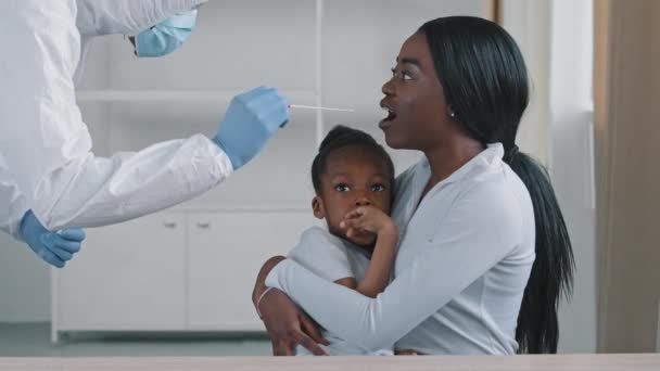 Coronavirus检测家族，身着防护服的医生从手持女儿的非洲裔美国女性单身病母的喉咙中取出拭子，PCR检测诊断方法 — 图库视频影像