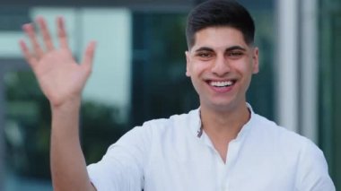 Genç pozitif Hintli blogcu el sallayarak aboneye selam veriyor ve kameraya bakıyor. İş görüşmesi etkinliği, video konferans uygulaması kullanılarak uzak iletişim