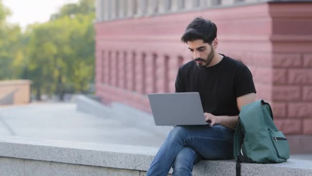 Millennial φοιτητής χρησιμοποιώντας πληκτρολόγηση laptop σε εξωτερικούς χώρους πληκτρολόγιο κοιτάζει οθόνη, φοβάται σηκώνει το χέρι του στο πρόσωπο, γενειοφόρος ινδός τύπος κάνει λάθος, ξέχασε τον κωδικό πρόσβασης, έλαβε δυσάρεστη e-mail, κακό μήνυμα — Αρχείο Βίντεο