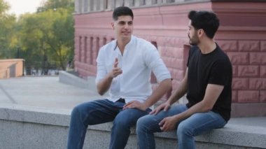 İki pozitif Hintli Arap açık havada oturmuş, konuşuyorlar, eğitim sorunları ya da iş sorunları hakkında konuşuyorlar. Kaygısız, siyah saçlı, orta doğulu erkek arkadaşlar hafta sonunun keyfini çıkarıyorlar.