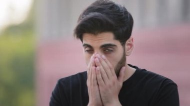 Stresli, sakallı, alerjisi olan genç bir adam dışarıda elleri önlerinde hapşırıyor. Hasta milenyum erkeği grip olmuş ya da nezle olmuş, alerji belirtileri gösteriyor. Sağlıksız adam virüs hastalığından muzdarip.