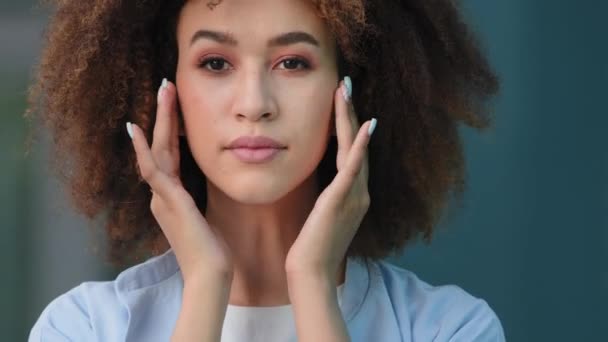 Retrato femenino de mujer al aire libre rizado joven hermosa africana chica americana modelo afro de raza mixta con piel perfecta oscura y maquillaje natural mirando la cámara preening toca la cara de las manos sonriendo — Vídeos de Stock