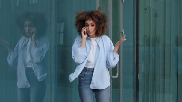 Fâché Afro Américaine fille Ethnique stressé femme debout dans la rue en ville à l'extérieur près du bâtiment parle sur téléphone mobile jurer querelle répondre appel conflit parler problème avec ordre sur smartphone — Video