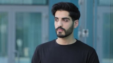 Çekici, esmer, Orta Doğulu bir adam geleceği düşünerek, iş gününü planlayarak başını çevirir, sana bakar ve gülümser. İnsan erkek yüzü, kendinden emin Hintli adam kameraya bakıyor.
