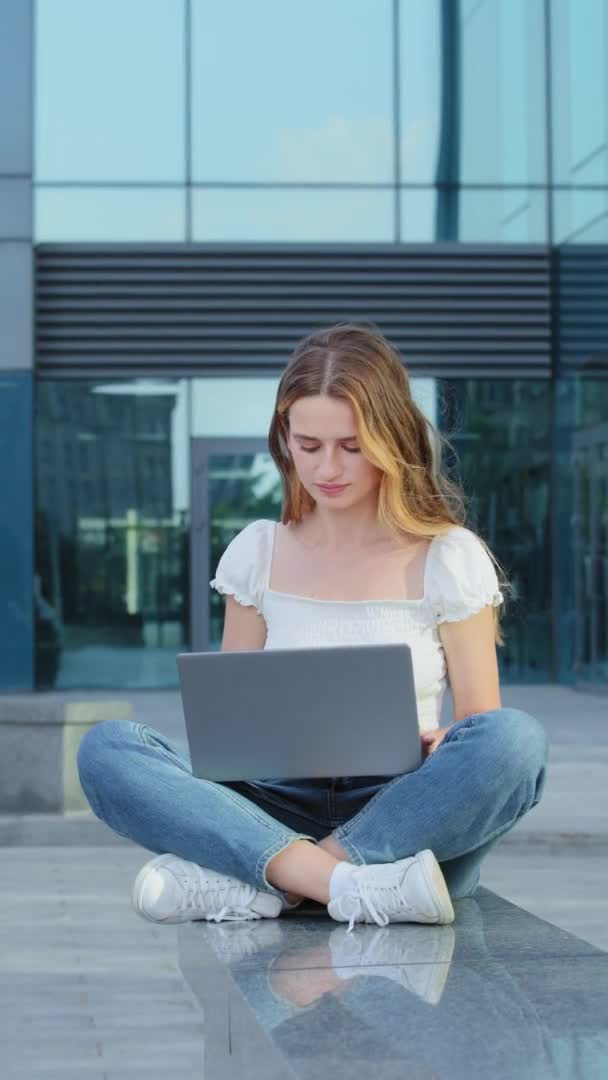 Vertikal video. Ung attraktiv tusenårig kvinna med hjälp av bärbar dator skriva på tangentbordet tittar på skärmen. Lycklig egenföretagare affärskvinna får kundorder via e-post, visar ok gest. — Stockvideo