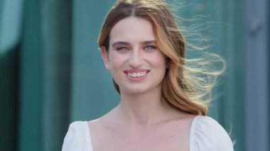 Gülümseyen mutlu, güzel, sağlıklı, dışarıda poz veren genç bir kadın. Çekici beyaz tenli, beyaz dişli gülüşlü Avrupalı beyaz kadın. Modern kendine güvenen kız diş hizmetleri reklamları yapıyor.