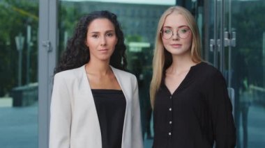 Kendine güvenen iki modern iş kadınının portresi, profesyonel liderler, koçlar veya yöneticiler. Sorumlu genç bayan iş arkadaşları banka müdürleri resmi kıyafetlerle dışarıda poz veriyorlar.