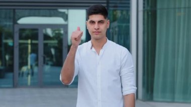 Beyaz gömlek giyen genç Hintli adam işe alım müdürü danışmanı ya da şirket çalışanı şirket ya da mağazayı ziyaret etmek için davetiyelerin arkasındaki binayı işaret ediyor. Tatmin olmuş Orta Doğulu müşteri