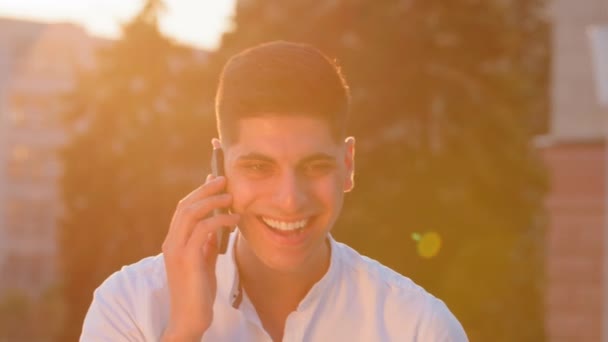 幸せなインドのアラビア人の男民族の男性のフリーランスのビジネスマンのユーザーの笑顔携帯電話のスマートフォンで話して呼び出します。自信を持って中東の男は屋外に立って電話に答える良いニュースを受け取った — ストック動画