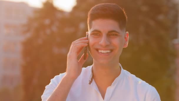 Joven indio árabe chico étnico masculino freelance empresario líder usuario hablando por teléfono móvil teléfono inteligente Feliz estudiante de Oriente Medio responder a la llamada de pie al aire libre en la ciudad llamando dispositivo inalámbrico — Vídeos de Stock