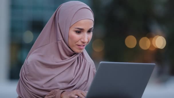 Close-up muszlim üzleti nő felhasználó diák iszlám arab lány visel hidzsáb nézi laptop képernyő ül a szabadban a városban olvasás jó hír nyer kapok pozitív eredményt kínál boldog győzelem — Stock videók