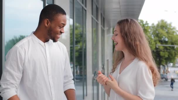 Pareja multirracial relación interracial hombre afroamericano y mujer caucásica hablando riendo en la calle edificio de la ciudad fondo. Multi-étnico novio y novia al aire libre comunicación — Vídeo de stock